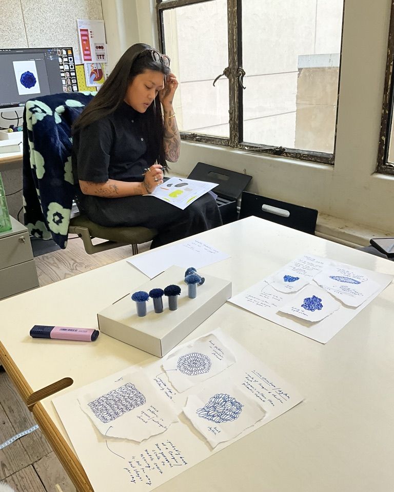 Carmellia working on a rug design at the studio desk